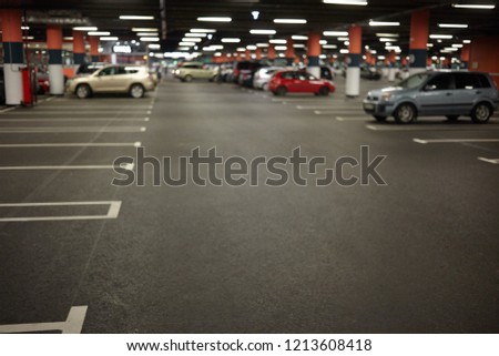 Horizontal picture of car parking or underground garage interior with neon lights and autocars parked. Buildings, urban constructions, space, transportation, vehicle and night city concept