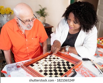 Horizontal portrait of an African American medical assistant playing a board game with an ederly caucasian man