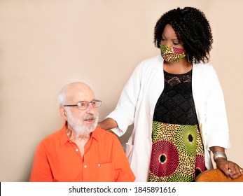 Horizontal portrait of an African American medical assistant wearing a mask and helping an ederly man at home in times of Covid19 pandemic - Shutterstock ID 1845891616
