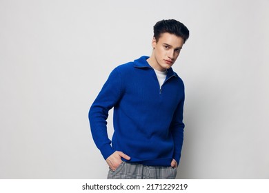 horizontal portrait of a handsome man in a stylish, blue zip-up sweater standing on a light gray background with his hands in his jeans pockets - Shutterstock ID 2171229219