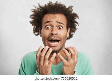 Horizontal portrait of nervous puzzled mixed race man gestures in panic, has disturbed and petrified expressions, finds out about death of relative or terrible accident, isolated over white background
