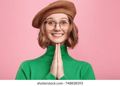 Horizontal portrait of pretty woman keeps palm together, has pleased expression, asks husband to buy her new coat. Glad attractive female makes request, pleads for mercy. Hopeful young adult - Shutterstock ID 748838593