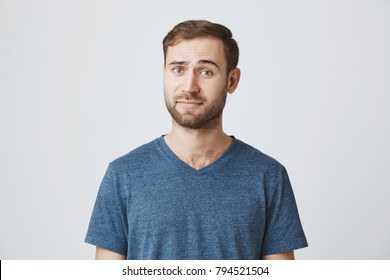 Horizontal Portrait Of Puzzled And Confused Man With Beard Dressed Casually, Looking At Camera With His Blue Eyes, Thoughtful, Not Knowing What Is Wrong. Human Feeling, Emotions, Face Expressions