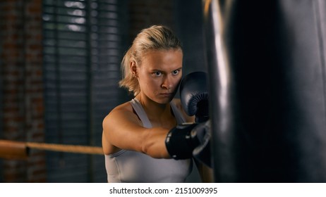 Horizontal Portrait Of Strong Woman Hitting Heavy Bag During Boxing Training