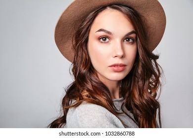 Horizontal portrait of stylish attractive female model wears summer clothes and brown hat with natural makeup posing on gray background in studio. Looking at camera