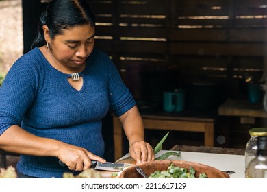 Horizontal Portrait Of A Young Mexican Woman Preparing Salad In A Rural Kitchen. Copy Space.	