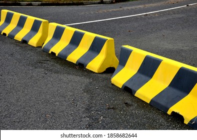 horizontal road marking lanes. highway concrete barriers on the road. vehicle collision lane separator. yellow color with black stripes. the road is not finished and ends in field concrete barriers