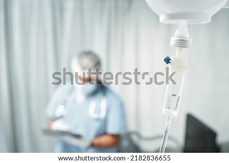 Horizontal selective focus shot of transparent bag full of medication fluid on pole connected with intravenous lines