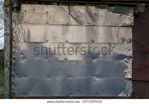horizontal shiny stainless steel sheets nailed to\
flat surface
