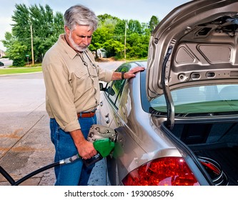 Horizontal Shot Of An Angry Older Man Pumping Gas As Fuel Prices Rise.  This Is A Revised Picture.