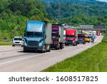 Horizontal shot of a blue semi climbing a hill on an interstate highway in heavy traffic.