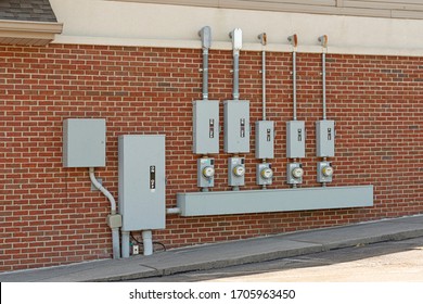 Horizontal shot of electric meters for a commercial strip center mounted on a red brick wall.