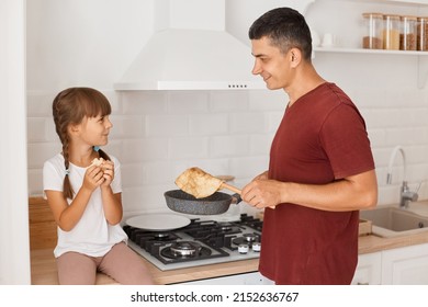 Horizontal Shot Of Father And Daughter Posing In Kitchen, Cooking Together, Frying Dessert For Breakfast, Standing Near Table And Gas Stove, Family Spending Time Together.