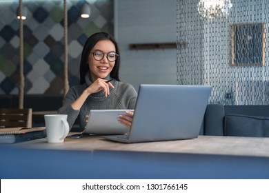 Horizontal shot of female asian woman that reading document with smile and pen in her hand at coworking place