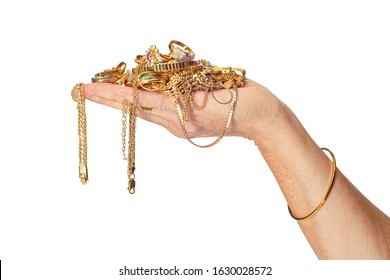 Horizontal shot of a woman’s hand holding a pile of gold jewelry some of which is hanging down from her hand. She is also wearing a bracelet. Isolated on white.  Copy space.