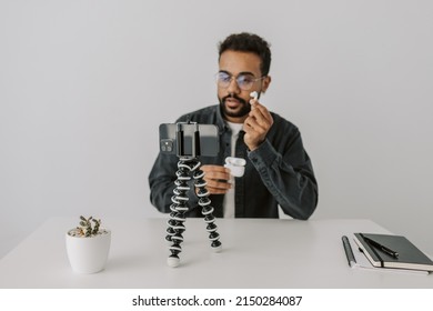 Horizontal Shot Of Handsome Black Man Vlogger Sitting In Living Room And Talking To Phone Camera