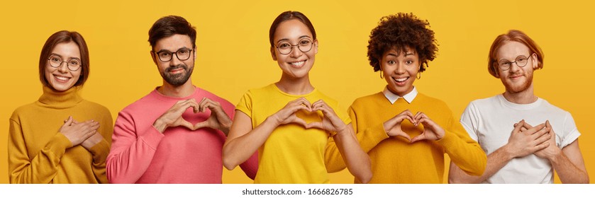 Horizontal Shot Of Happy Women And Men Show Heart Gesture, Express Love, Say Be My Valentine, Keep Hands On Chest, Feel Thankful, Isolated On Yellow Background, Confess In Truthful Feelings.