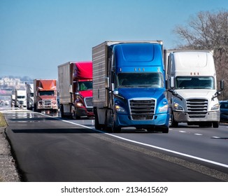Horizontal shot of a long convoy of trucks on an interstate highway.