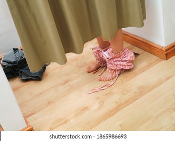 Horizontal Shot Of Low Section Of A Teenage Girl Behind Curtains Undressing To Try New Clothes In A Fitting Room In A Store.