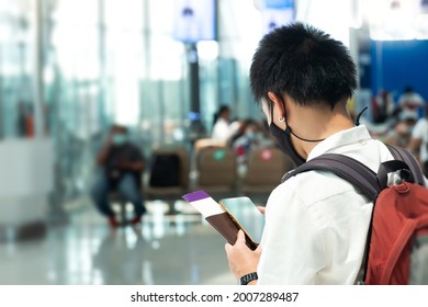 Horizontal Shot Of Man Poses In Crowded Airport Terminal, Vacation  Wears Medical Mask During Coronavirus Crisis. Health Care, 
Vacation Or Traveling Concept.