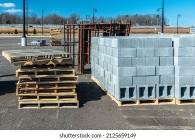 Horizontal shot of new cinderblocks stacked on wooden pallets at a large industrial construction site.