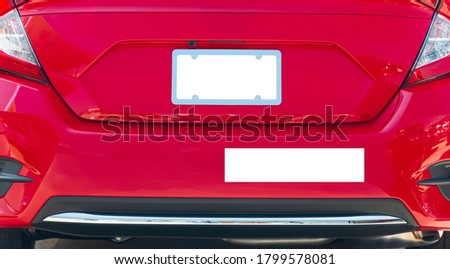 Horizontal shot of the rear of a red car with a blank white license plate and bumper sticker.  Good copy space.