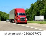 Horizontal shot of a red eighteen wheeler semi on the interstate with copy space. Heat waves rising from the hot asphalt creates a blurring effect on background trucks and foreground pavement.