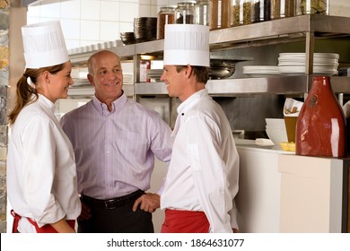 Horizontal Shot Of A Restaurant Manager Talking To Male And Female Chefs In A Commercial Kitchen.