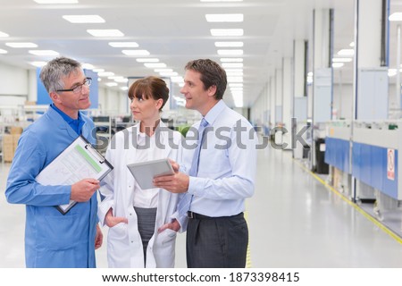 Horizontal shot of a scientist, technician and a businessman under discussion on a factory floor with copy space.
