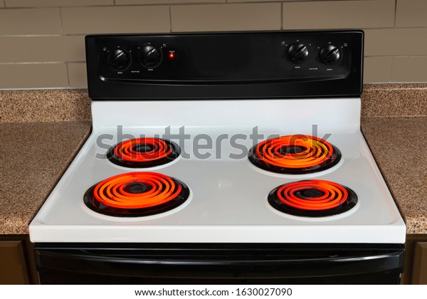 Horizontal shot of the\
stovetop of an electric range with all the burners turned to high\
and glowing red.