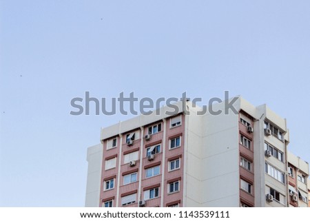 Horizontal shot of tall concrete red covered mass housing building facade in Izmir at Turkey with blue sky background