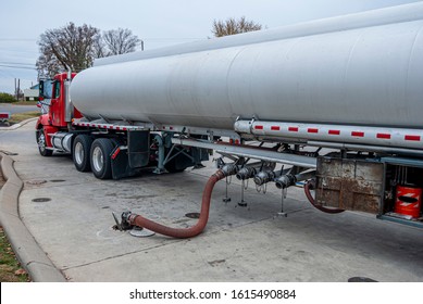 Horizontal Shot Of A Tanker Fuel Truck Filling The Underground Tank At A Gas Station.