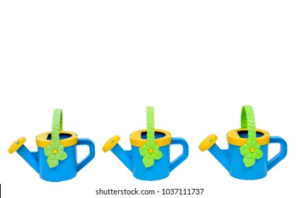 Horizontal shot of a watering pail border across the bottom consisting of three blue and yellow watering cans with green handles on a white background.  Lots of copy space.