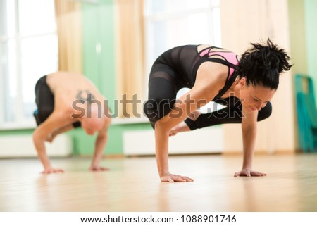 Horizontal shot of a woman and man working out at yoga studio doing balancing asana. Mature couple doing handstand while practicing yoga together. Relationships, sports, lifestyle