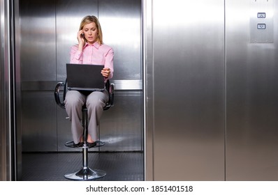 Horizontal shot of a young businesswoman using mobile phone sitting on stool in lift while working on a laptop with copy space. - Powered by Shutterstock