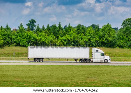 Horizontal side view shot of a white tractor-trailer with a blank trailer that would make great copy space.