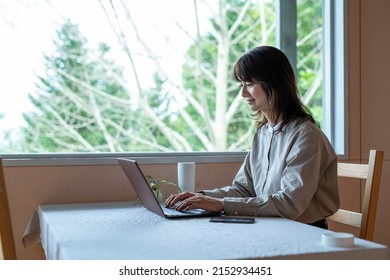 A horizontal side view shot of Woman Teleworking at Cafe in the Forest