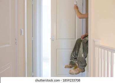 A horizontal side view of an unrecognizable painter painting the door with white color