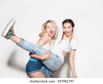 Horizontal Studio Shot Of Two Young Friends Laughing And Having Fun. 