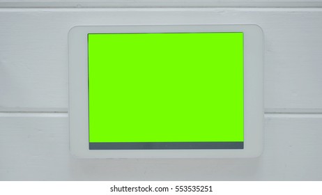 Horizontal tablet computer with green screen on white wooden background. Technology and internet concept