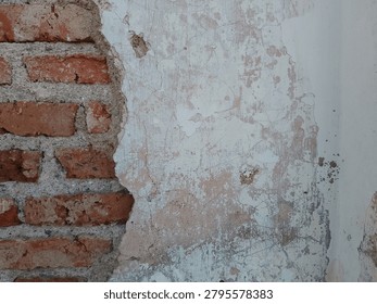 horizontal top view of a rustic brick wall exposed under weathered cracked stucco plaster, displaying beautiful orange and white contrast.