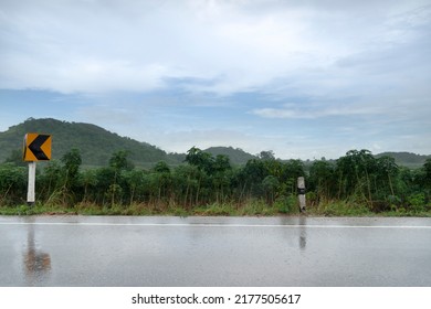 Horizontal view of asphalt road with wet surface in Thailand. Environment of rainy time. and background of cassava plantation and green mountains with bring down the rain in a line. under the sky.