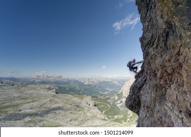 Horizontal view of an attractive female climber on a steep Via Ferrata in the Italian Dolomites with a great view behind