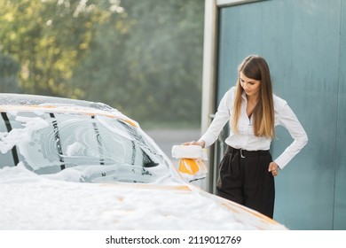 Horizontal View Of Car Cleaning At Self Wash Service. Caucasian Business Woman Wearing On A White Shirt And Black Trousers While Washing Rearview Car Mirror With Sponge And Foam