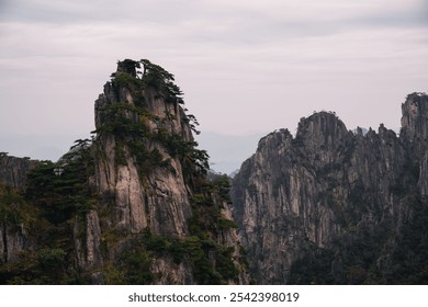 Horizontal view of dramatic wall of rock covered by pines on a cloudy day of autumn in the Yellow Mountain, Huangshan, China