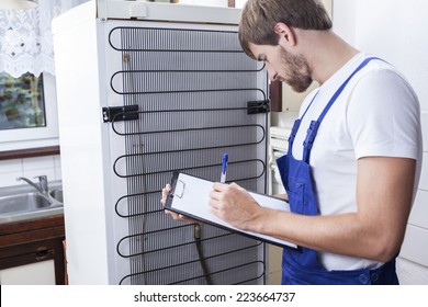 Horizontal View Of Handyman During Fridge Repair