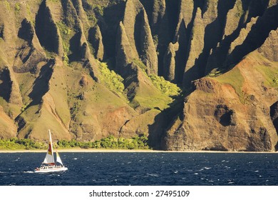 Horizontal view of Kauai's famous Na Pali coast, inaccessible by road.  A sailboat is traversing left to right. - Powered by Shutterstock