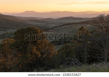 Horizontal view of the Pine Valley Mt. Utah from the top of a hill above the Water Canyon trail. The setting sun paints the landscape with warm light while a creek winds through the valley below.