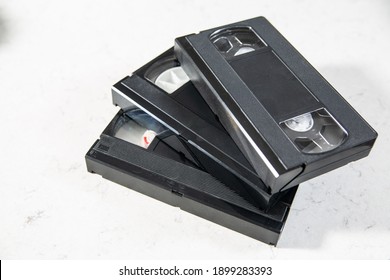 Horizontal View Of Three Videotapes, Video Cassettes On A White, Marble Background. A Pile Of Vintage VHS Tapes Without Box, Case, Cover.