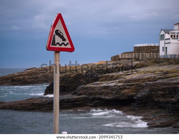 Horizontal view of\
warning traffic sign of end of road and fall into the sea and\
Ringlo village in the\
background.